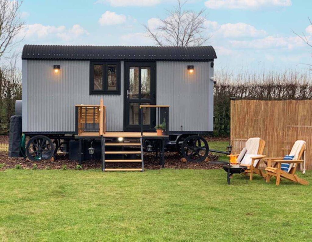 Ash Hut, the grey shepherd hut, with its decking and garden chairs