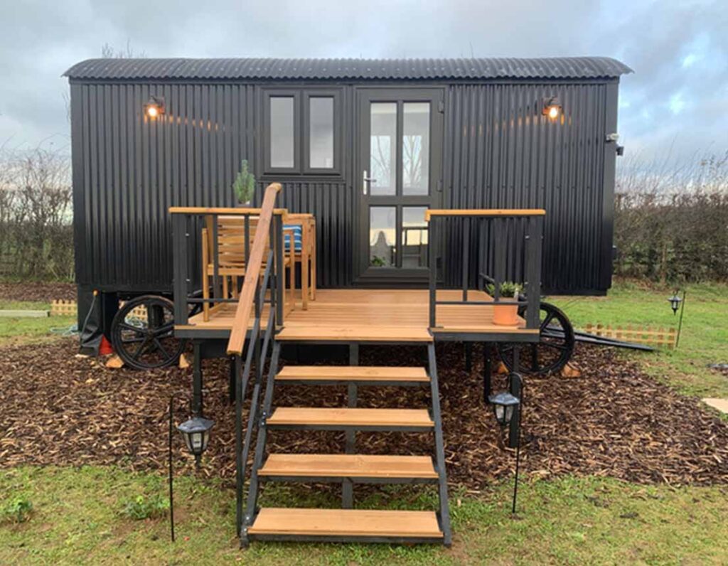 Oak Hut, the black shepherd hut, with steps up to its decking